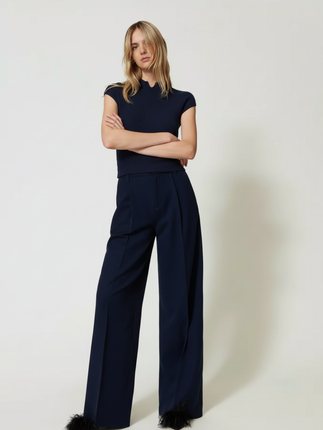Model trägt TWINSET Nadelstreifen Palazzohose in Dunkelblau mit weitem Bein und passendem Oberteil.